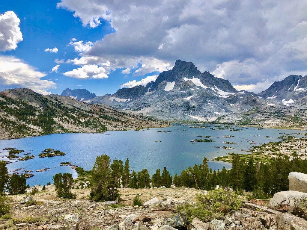 Blue alpine lake below granite peaks and clouds